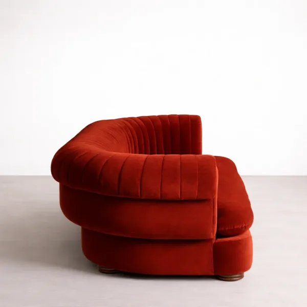 Side view of red velvet Chesterfield sofa with rolled arm and channel tufting