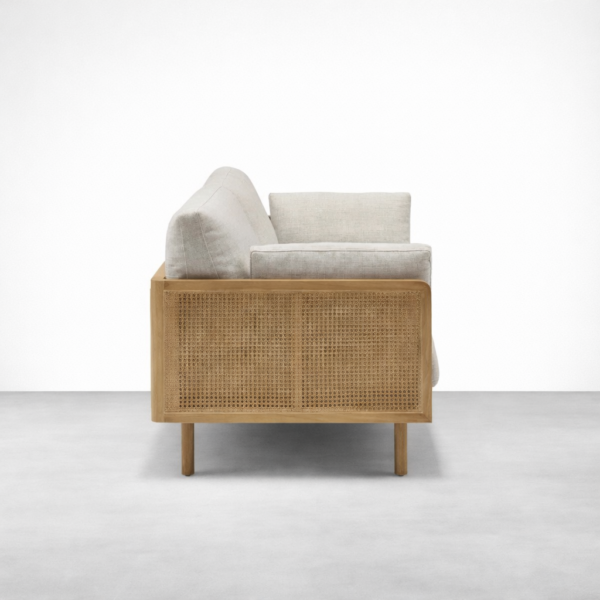 Side view of teakwood rattan sofa with beige fabric cushions by INTERIORZE
