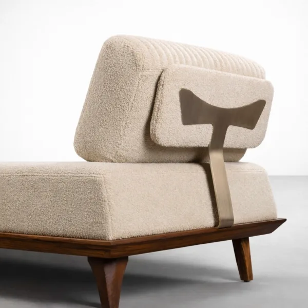 Close-up of ivory bouclé daybed sofa showing metal support bracket and teakwood base detail
