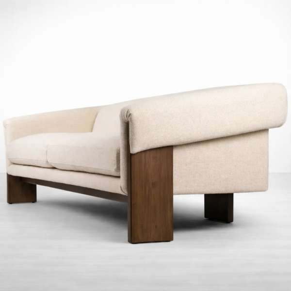 Rear angled view of teakwood sofa with cream fabric and warm wood polish by INTERIORZE