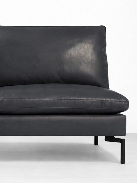 close up view of black leather sofa with supportive cushions and metal legs by INTERIORZE