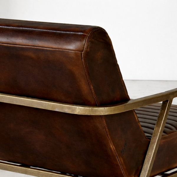Backrest detail of brown leather lounge chair with antique brass arm frame