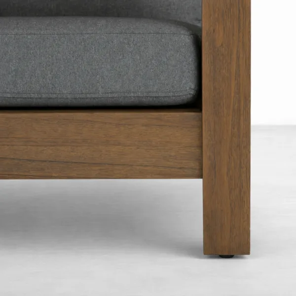 Close-up of teakwood outdoor sofa frame finish and charcoal cushion upholstery by INTERIORZE
