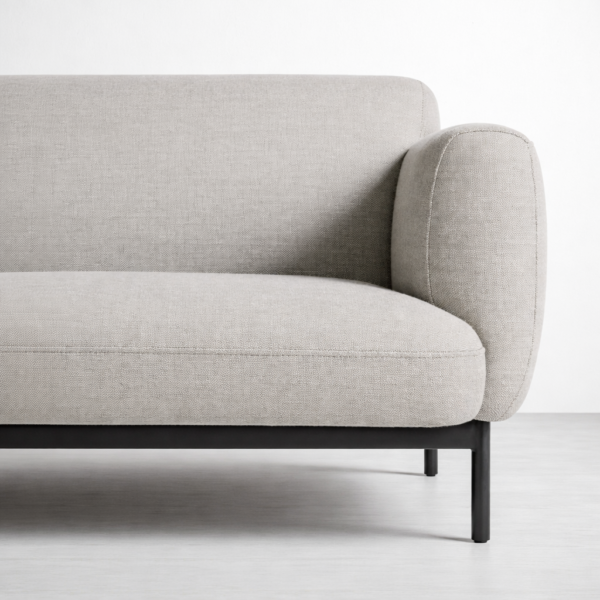 Close-up of grey linen sofa with metal base by Interiorze showing rounded arm and seat