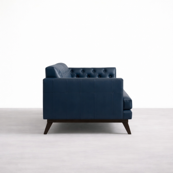 Side view of navy blue tufted leather sofa with teakwood legs by Interiorze