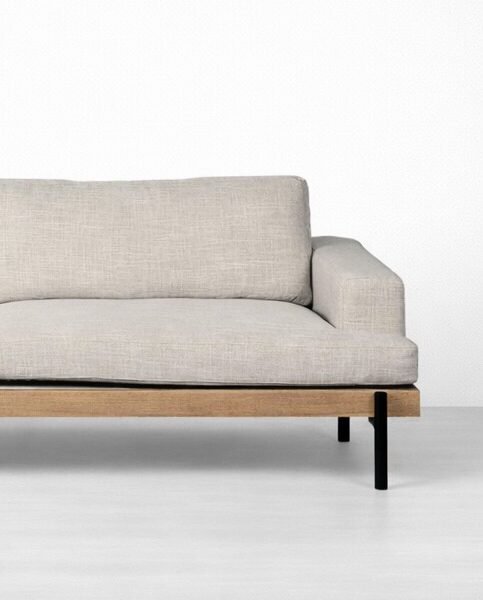 Close-up of beige linen sofa with teakwood base and metal legs by Interiorze