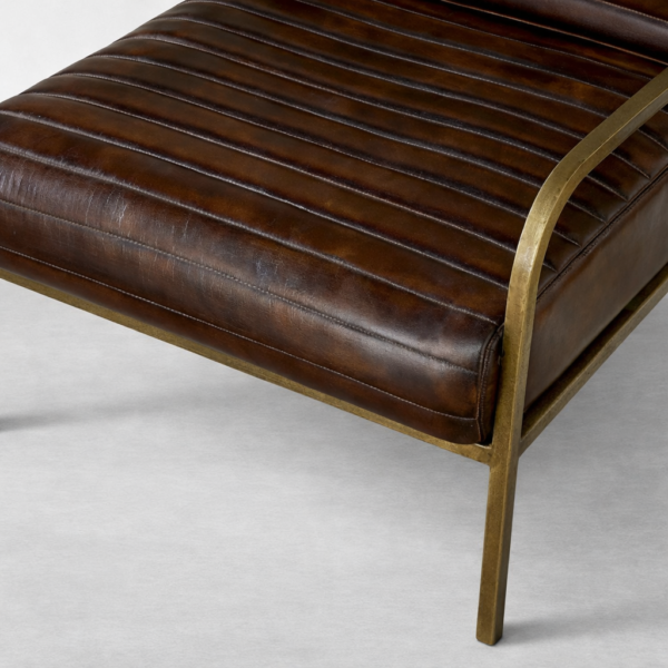 Close-up of channel-stitched brown leather seat cushion on brass frame lounge chair