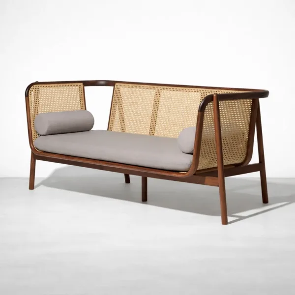 Angled view of teakwood rattan sofa with cane side panels and grey cushion by INTERIORZE