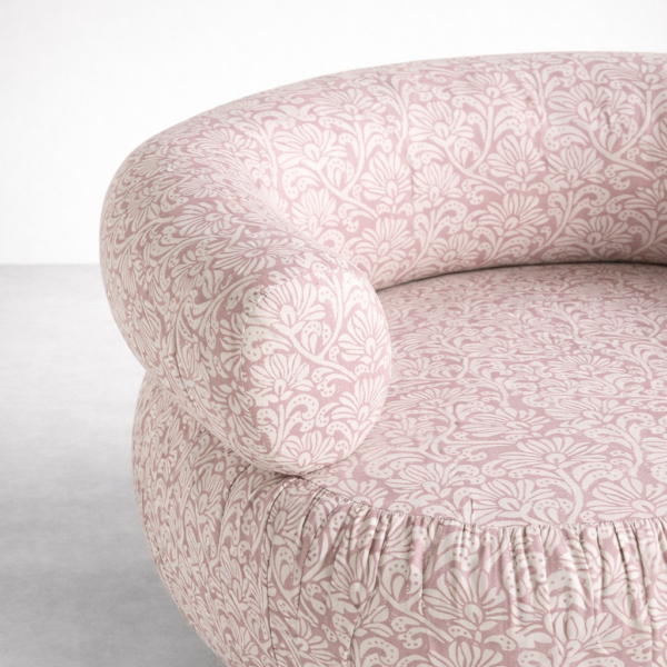 Blush pink floral swivel chair upholstery close-up with rounded armrest