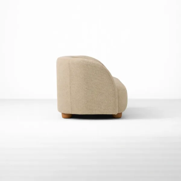 Side profile of beige upholstered sofa with curved back by INTERIORZE