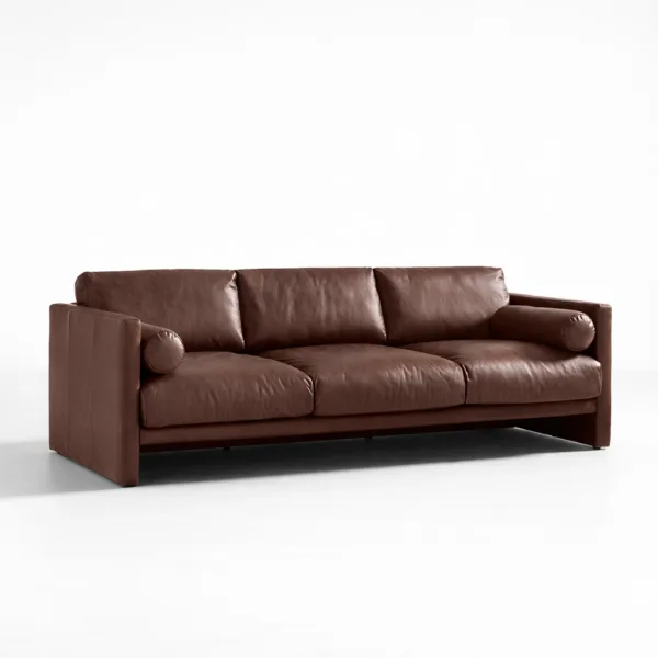Angled view of INTERIORZE brown leather sofa showing deep cushions and bolsters