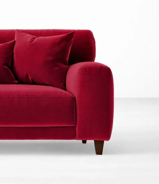 Red velvet loveseat close-up showing cushions and rounded arm, INTERIORZE RUBY.