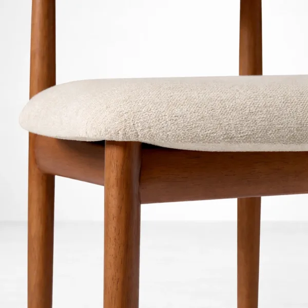 Close-up of ivory bouclé fabric and teakwood finish on dining chair