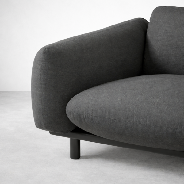 Close-up of INTERIORZE Drift charcoal fabric 2 seater sofa showing rounded arm, plush seat cushion, and black base