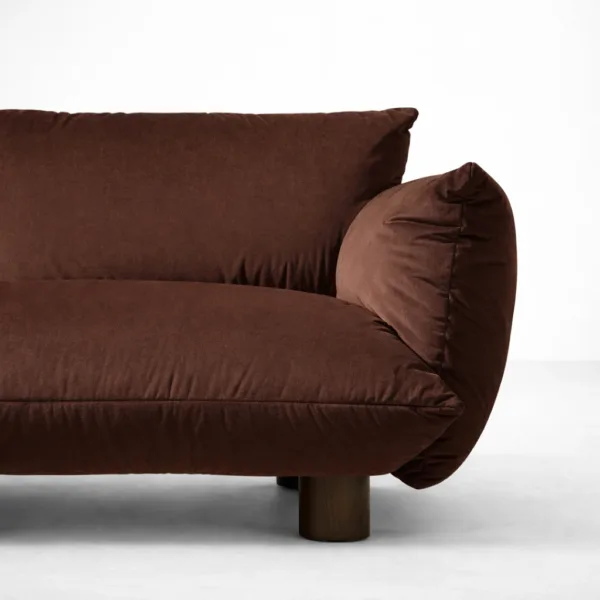 Close-up of INTERIORZE Cocoa Loft brown suede fabric 2 seater sofa showing rounded side bolster, plush seat cushion, and wooden leg