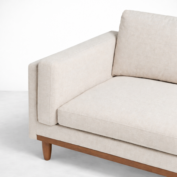 Beige sofa fabric and cushion detail with teak base close-up