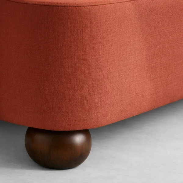 Close-up of upholstered bed base and wooden ball leg in dark walnut finish