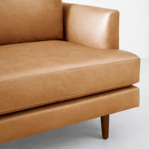 Tan leather sectional sofa seat and arm detail with neat stitching by INTERIORZE