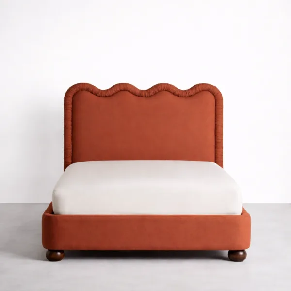 Upholstered bed front view with scalloped headboard in terracotta fabric
