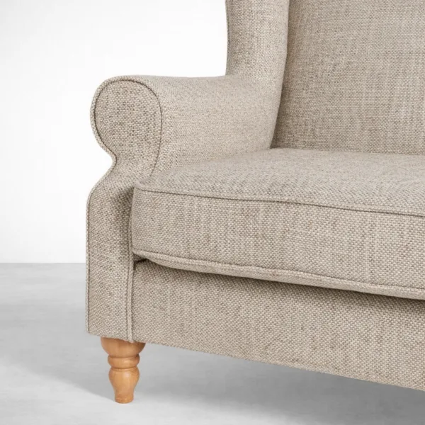 Beige wingback sofa fabric texture and stitching close-up with teakwood leg detail
