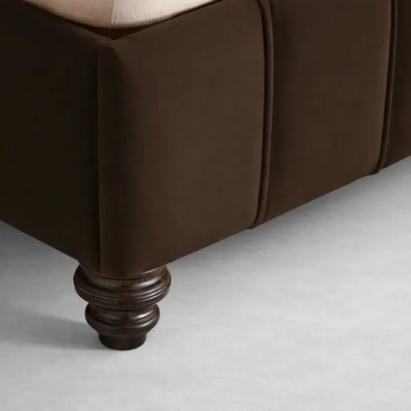 Close-up of brown upholstered bed base and dark walnut turned leg