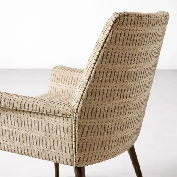 Close up of beige patterned upholstery and teakwood leg on INTERIORZE dining chair