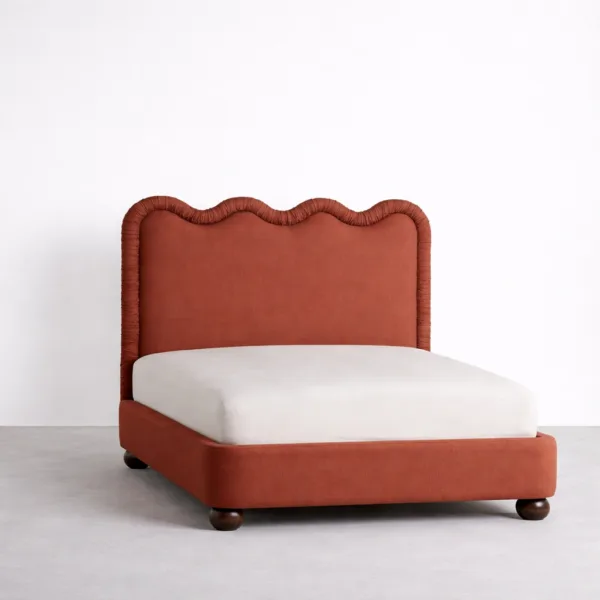 Upholstered bed with scalloped headboard in terracotta fabric angled view