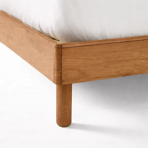 Teakwood bed leg and corner detail with warm polish finish on an upholstered teakwood bed