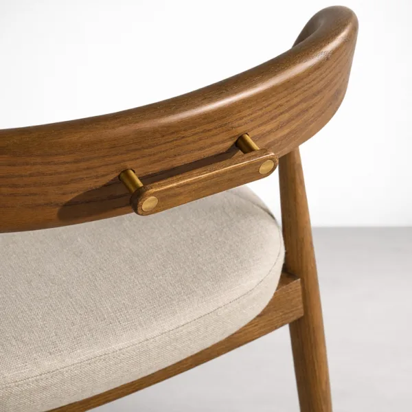 Close up of teakwood backrest and brass accent on INTERIORZE dining chair