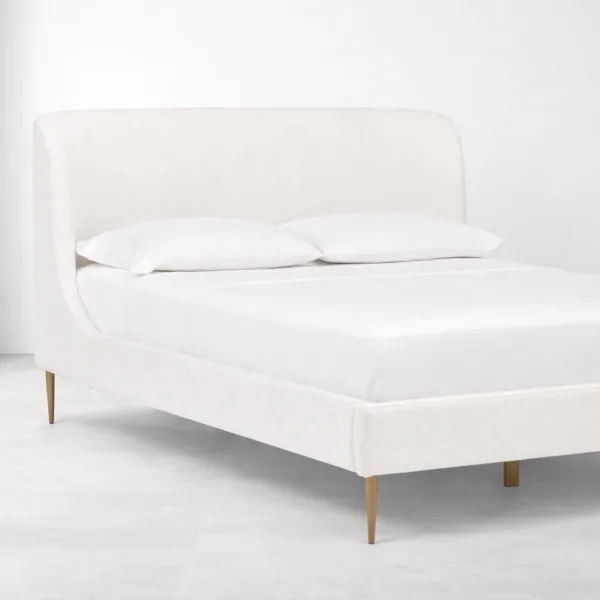 Bouclé upholstered bed angle view showing curved wraparound headboard and slim tapered legs