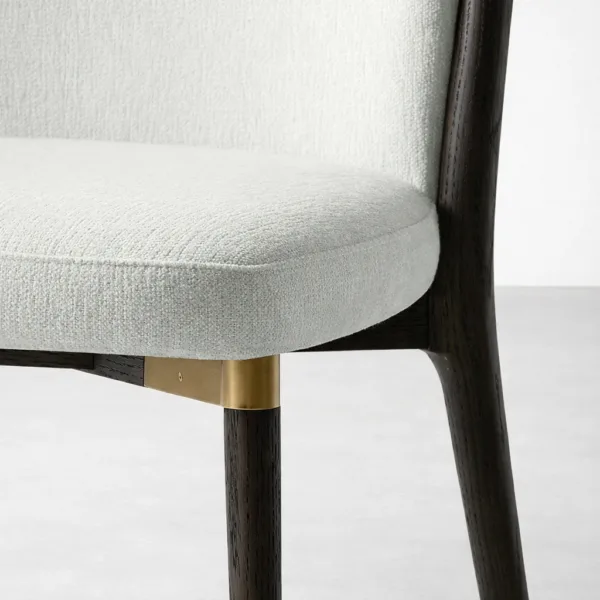 Close up of cream upholstered seat and brass accent on INTERIORZE teakwood dining chair