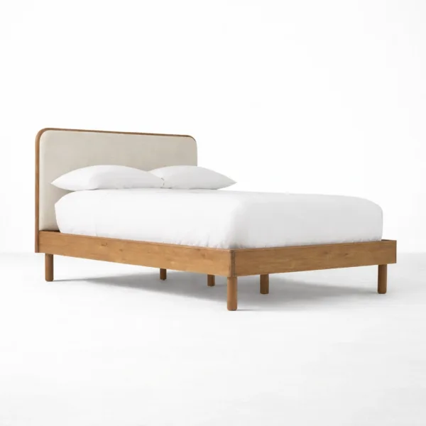 Upholstered teakwood bed angle view showing warm teak frame and upholstered headboard panel