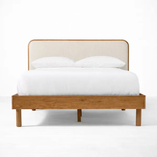 Upholstered teakwood bed with rounded frame headboard and beige fabric panel by INTERIORZE