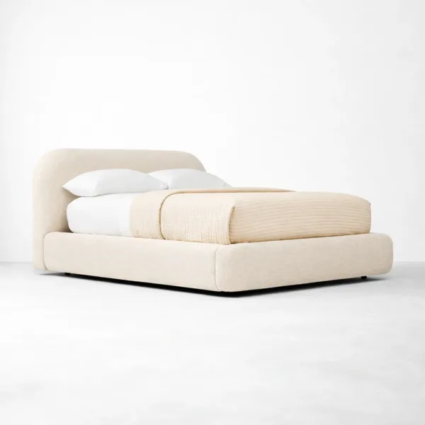 Fully upholstered bed angle view showing padded frame and rounded headboard in neutral upholstery