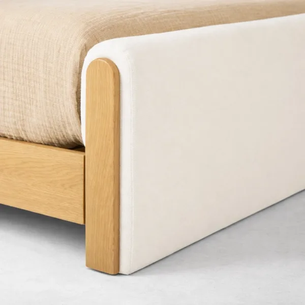 Upholstered footboard detail of an upholstered teakwood bed with rounded teak corner post