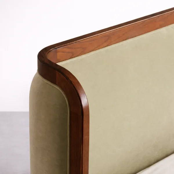 Close-up of rounded teakwood corner frame with olive green upholstered panel on headboard