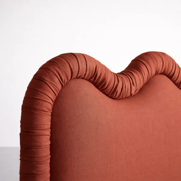 Close-up of scalloped upholstered headboard showing padded border detail and fabric texture