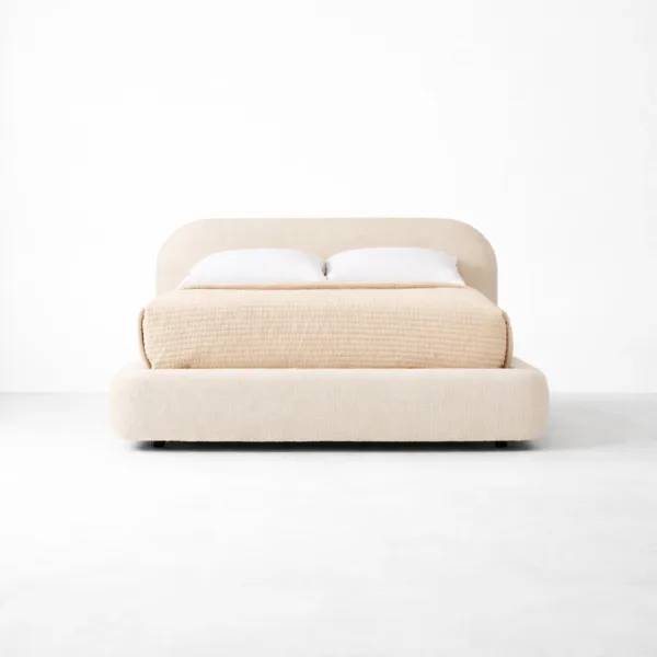 Fully upholstered bed with rounded headboard in warm beige fabric by INTERIORZE