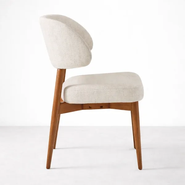 Beige upholstered dining chair side view showing wide backrest and teakwood legs