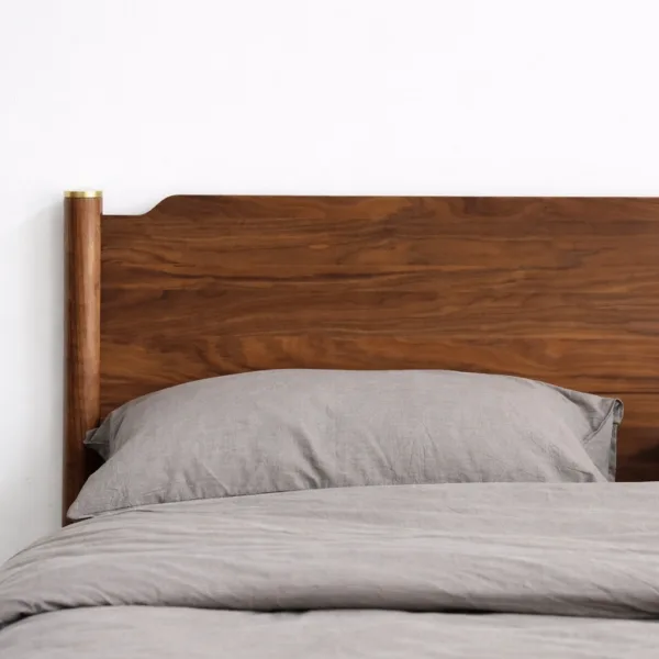 Close-up of teakwood headboard with natural grain pattern and brass accent