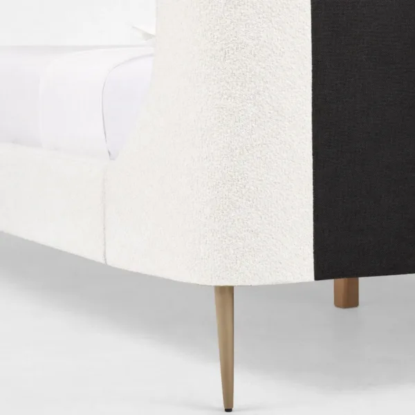 Bouclé upholstered bed side detail showing wraparound headboard curve and tapered leg finish