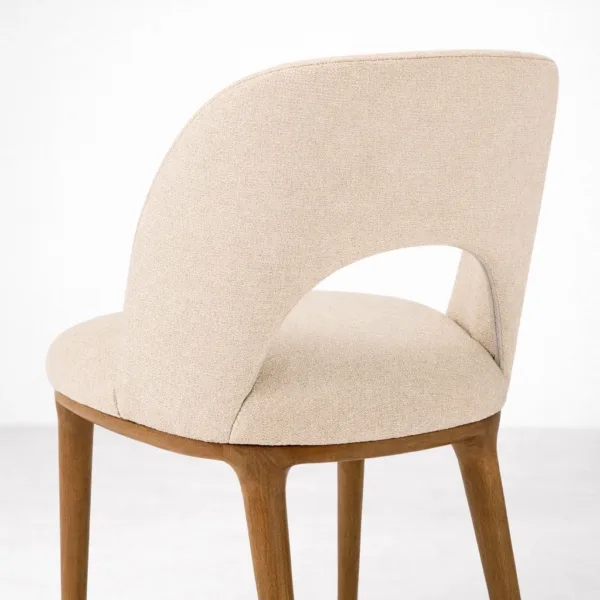 Upholstered teakwood dining chair side angle showing curved backrest and cut-out detail