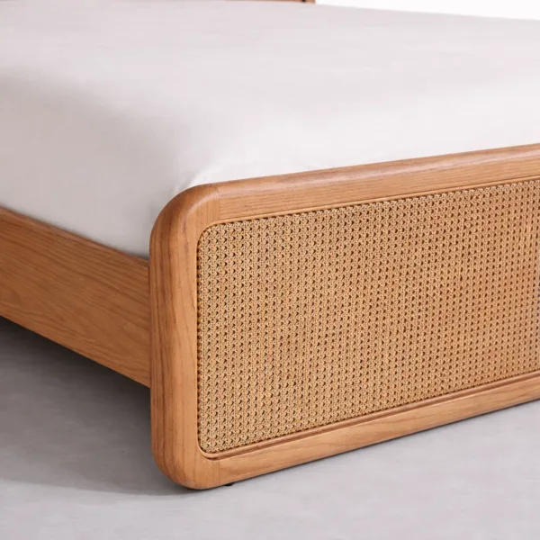 Teakwood cane bed footboard close-up showing cane weave panel and rounded teakwood frame