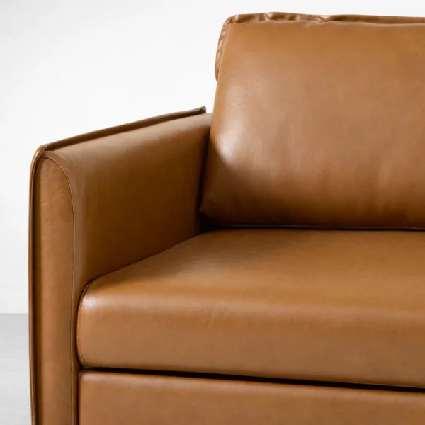 Close-up of INTERIORZE caramel leatherette sofa cum bed arm and cushion