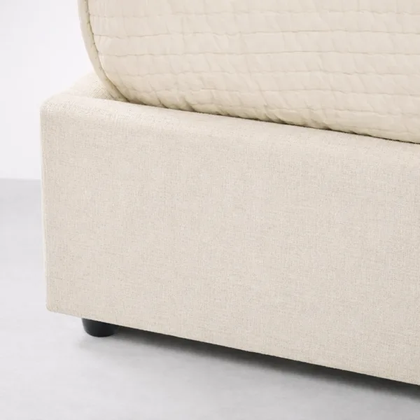 Close-up of beige upholstered bed base with neat tailoring and sturdy footing