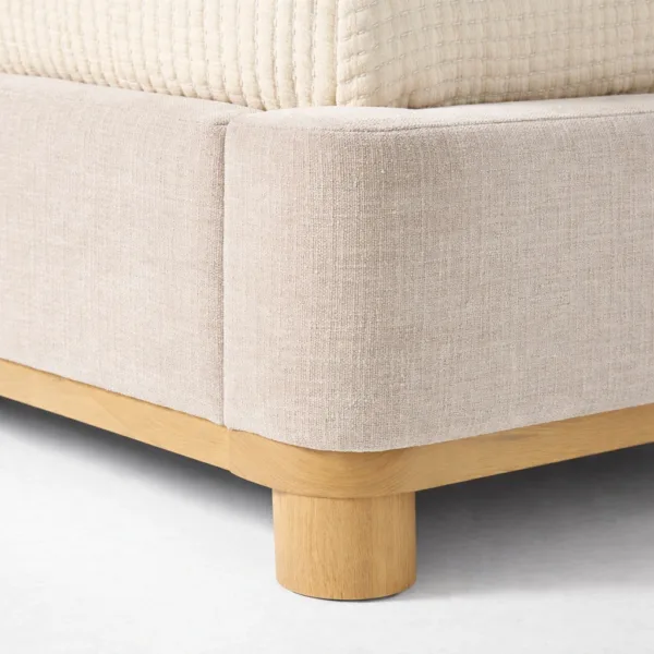 Teakwood base and leg detail of an upholstered teakwood bed with upholstered frame