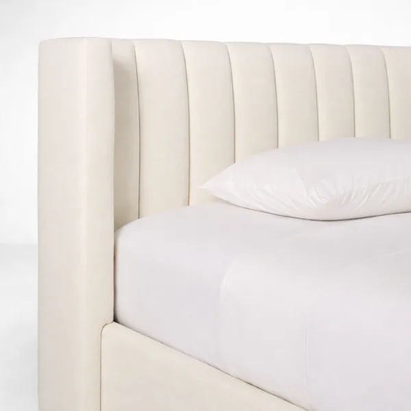Close-up of channel wing headboard on ivory upholstered bed with teakwood frame